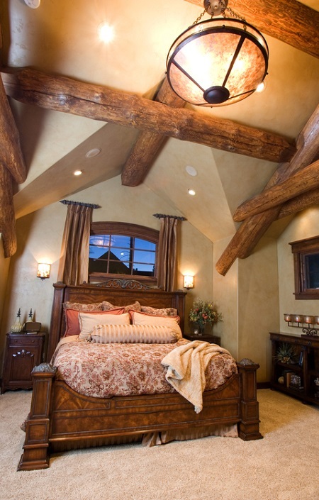 Dormitor amenajat in stil rustic, cu patul si grinzile din lemn masiv, la vedere