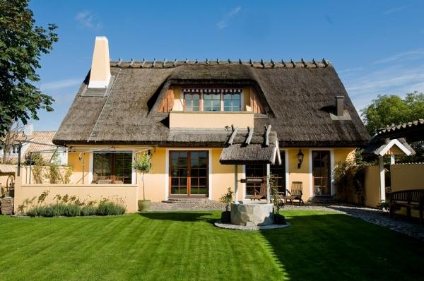 O casa ca-n povesti: acoperis din stuf, gard de piatra, poarta din fier forjat si o curte acoperita cu piatra naturala si iarba
