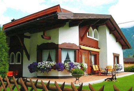 O casa frumoasa cu finisaje din lemn ce decoreaza acoperisul, geamurile si o parte a fatadei