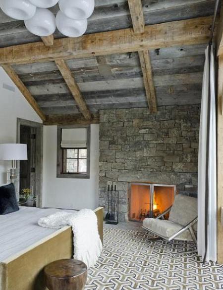 Dormitor rustic cu grinzi de lemn si zid din piatra